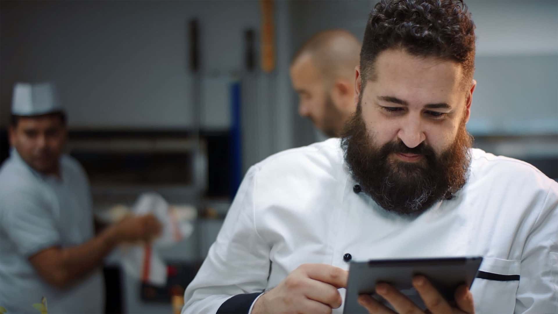 Executive chef in the kitchen who is using a tablet to control his smart commercial oven