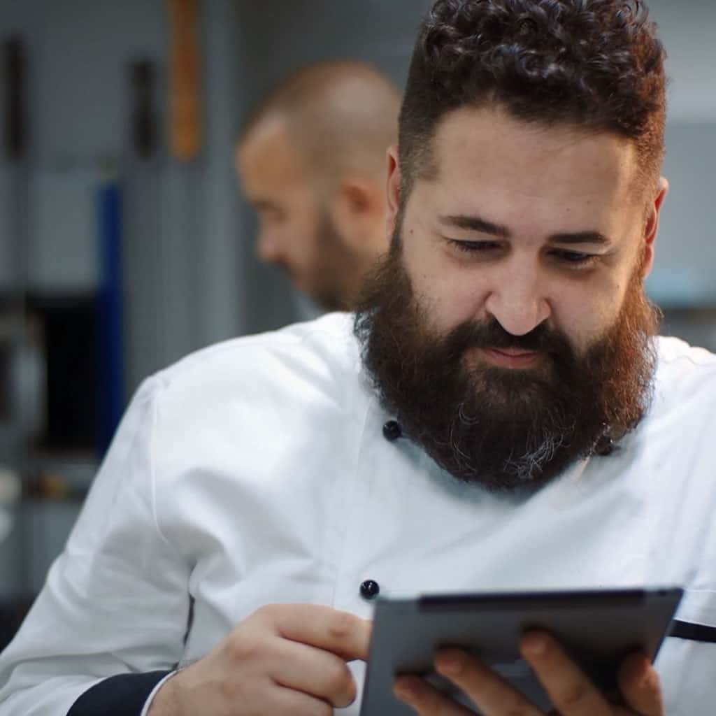 Executive chef in the kitchen who is using a tablet to control his smart commercial oven