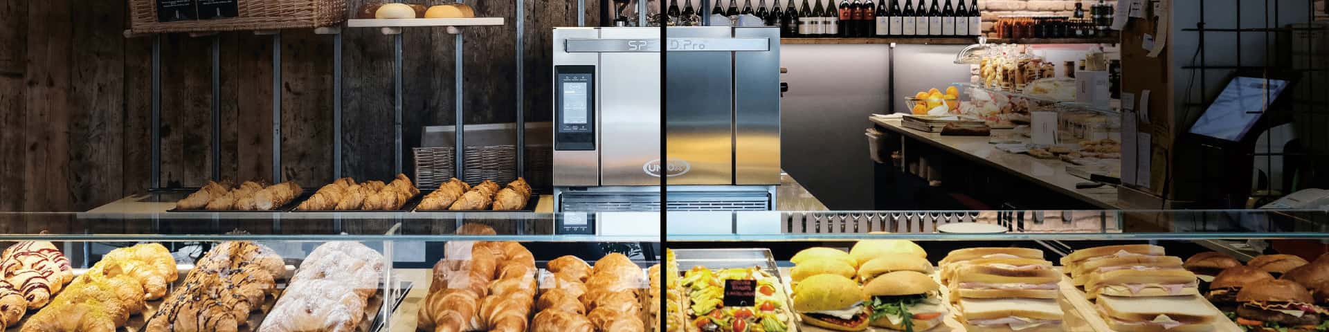 A deli with half the counter housing pastries and the other has sandwiches, Unox Speed.pro speed oven can be seen behind the counter.