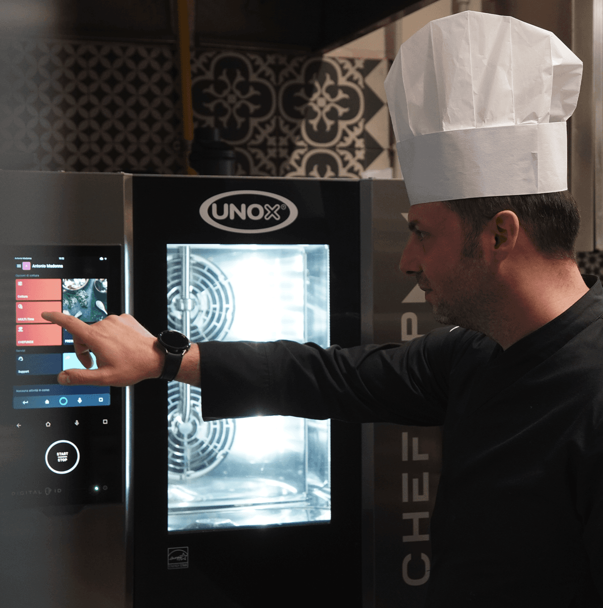 Ein Koch bedient das Touchscreen-Bedienfeld eines intelligenten Profi-Ofens von Unox in einer Restaurantküche