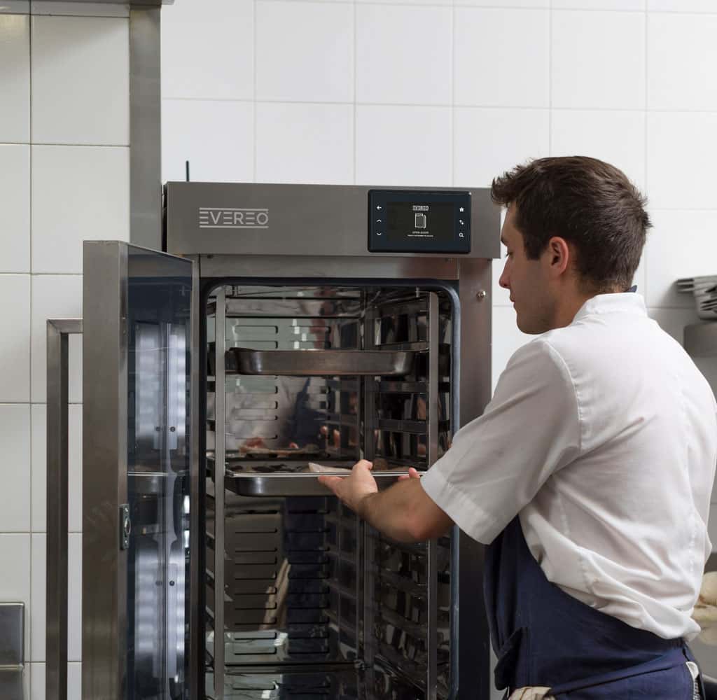 Professionista di cucina inserisce una teglia con cibo pronto da servire nel sistema Unox EVEREO per la conservazione degli alimenti caldi.