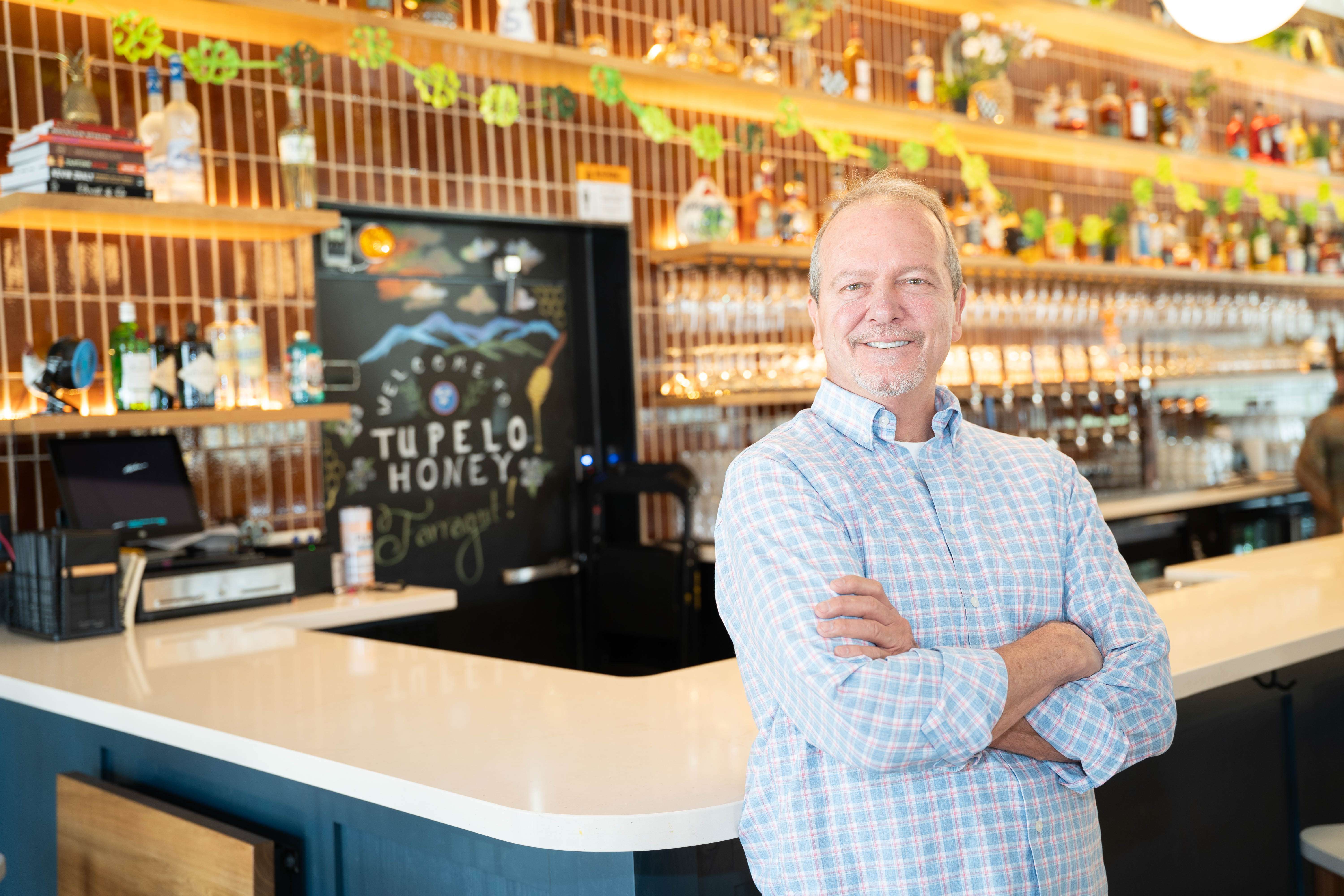 Le gérant du restaurant se tient les bras croisés devant le comptoir du bar de Tupelo Honey.