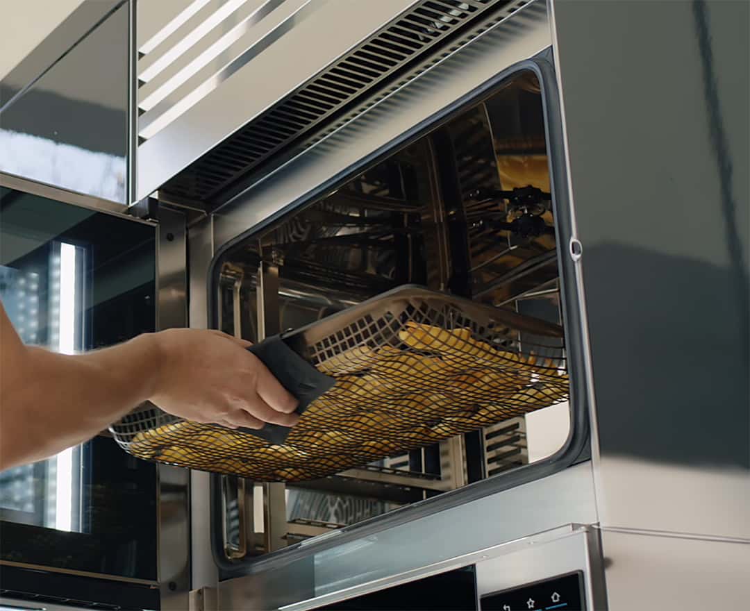 person, die ein tablett in den unox cheftop vista ofen einschiebt