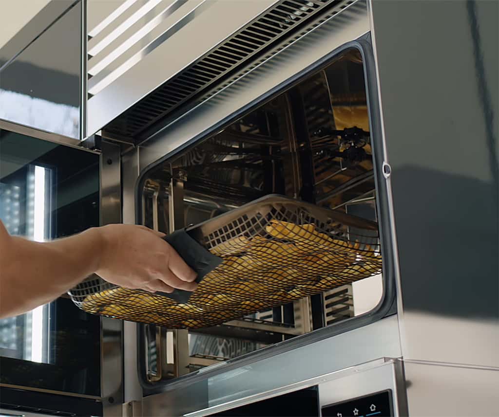 person, die ein tablett in den unox cheftop vista ofen einschiebt