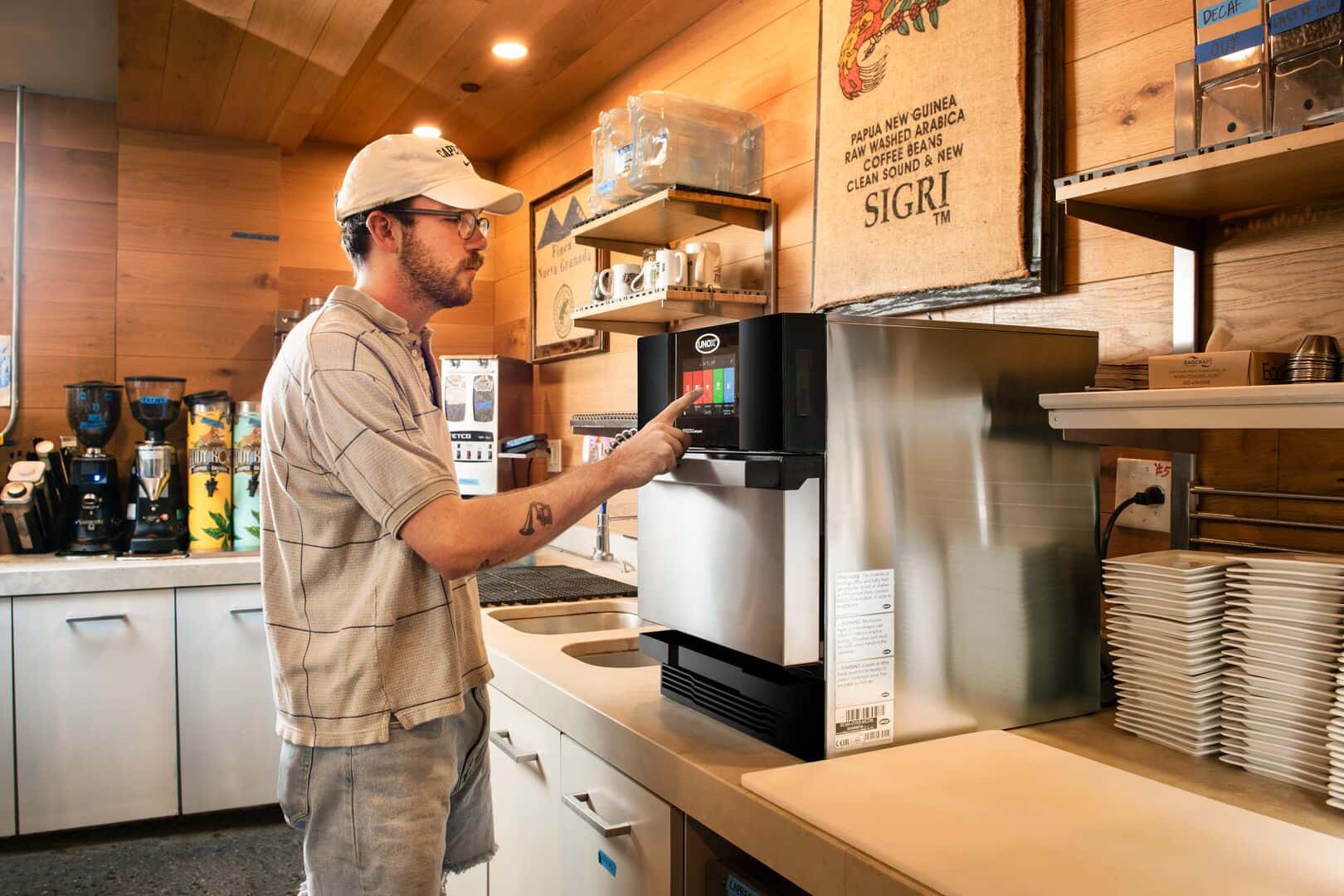 A man working in a quick-service restaurant uses a Unox speed oven, effortlessly interacting with its touchscreen panel.