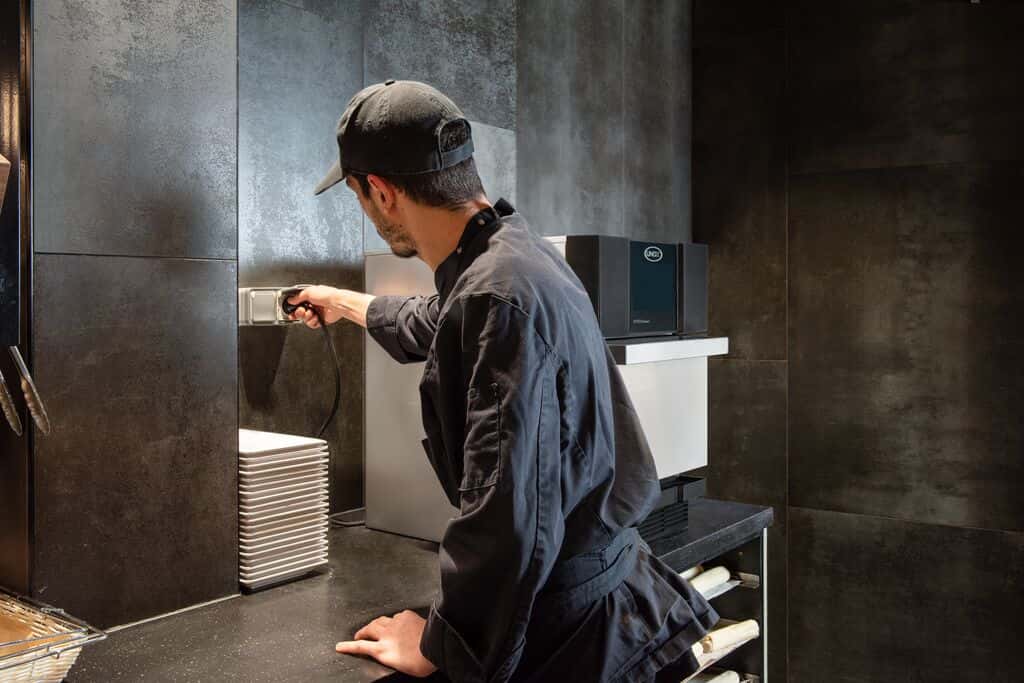 A coffee shop employee in a black shirt easily plugs in a Unox speed oven on the counter.