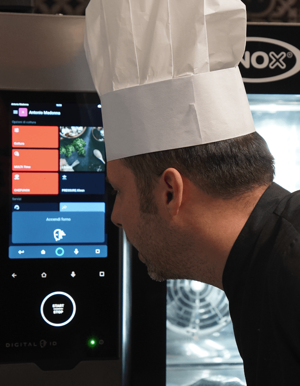 Koch, der Sprachbefehle über das Touchscreen-Display eines intelligenten Unox-Professioneller Backofen nutzt